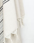 Close-up image of grey stripes on a cream colour plain colour with linen & cotton blends with knotted fringe.