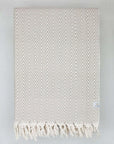 Folded handwoven extra-large blanket with a chevron pattern in beige colour.