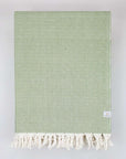 Folded handwoven large-size blanket with a diamond pattern in green colour.