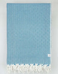 Folded handwoven large-size blanket with a diamond pattern in petrol colour.