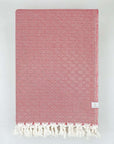 Folded handwoven large-size blanket with a diamond pattern in red colour.