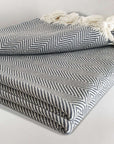 Stylish folded handwoven %100 cotton blanket with a herringbone pattern in grey colour.