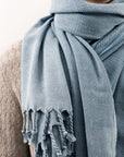 Close-up image of a 100% cotton scarf in plain grey colour with knotted fringe.